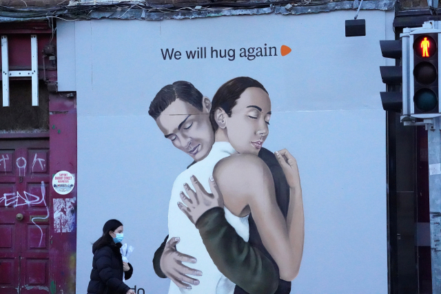 22일(현지시간) 영국 아일랜드 더블린의 한 거리에 ‘우리는 서로를 다시 안아 줄 거예요’라고 적힌 대형 포스터가 내걸렸다. 영국에서도 코로나19 재확산세가 심각한 가운데, 마스크를 착용한 한 여성이 이 포스터 앞을 지나가고 있다. 영국은 내달 1일부터 백신 접종을 시작해 4월까지 완료할 계획이다. 로이터연합뉴스
