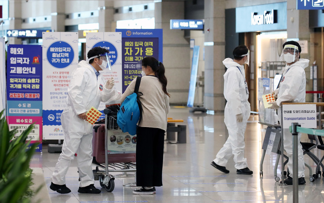 영종도 인천국제공항 제1터미널 입국장에서 해외입국자들이 신종 코로나바이러스 감염증(코로나19) 관련 안내를 받고 있다. 연합뉴스