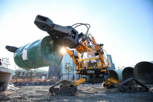 드럼통을 양팔 작업기로 들어 올리고 있는 재난대응 특수목적기계. 한국생산기술연구원 제공