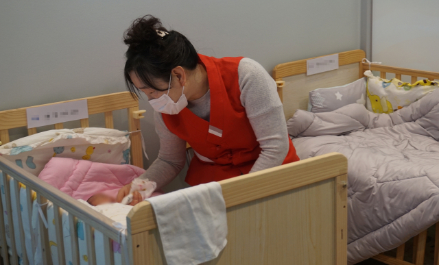 영유아 생명권 보호를 위해 ㈔국민행복실천운동본부가 2019년 부산 금정구 두구동 홍법사 내에 개소한 ‘행복드림센터(일명 라이프가든)’ 아가방에서 지난 2일 자원봉사자가 아이를 돌보고 있다. 라이프가든은 ‘베이비박스’와 달리 상담과 소통을 통해 아이의 안전과 부모의 결정에 도움이 되는 기회를 제공하고 있다. 김은영 논설위원