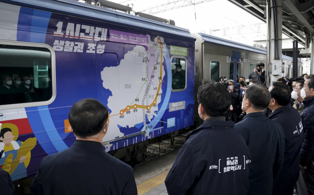 문재인 대통령이 지난달 25일 부산 부전역에서 열린 ‘동남권 메가시티 구축 전략 보고’에 참석, 부전역 플랫폼에서 열차에 래핑된 자료를 보며 송철호 울산광역시장의 ‘생활 행정공동체 전략 보고’를 듣고 있다. 연합뉴스