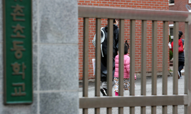 2021학년도 신학기 개학일인 2일 오전 광주 서구 한 초등학교에서 학부모가 아이의 등교를 돕고 있다. 지난해에는 고등학교 3학년만 매일 등교했으나 올해에는 사회적 거리두기 2단계 이하에서 유치원생과 초등학교 1~2학년도 매일 등교 수업을 한다. 연합뉴스. 해당 사진은 기사와 관련없음