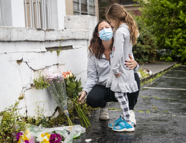 17일(현지시간) 미국 조지아주 애틀랜타의 마사지업체 ‘골드 스파’ 앞에서 한 시민이 딸과 함께 전날 이곳에서 발생한 총격 사건의 희생자들을 애도하며 조화를 놓고 있다. AP연합뉴스
