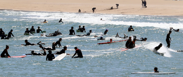 올해 4월 부산 해운대구 송정해수욕장에서 서퍼들이 파도를 타고 있는 모습. 부산일보 DB