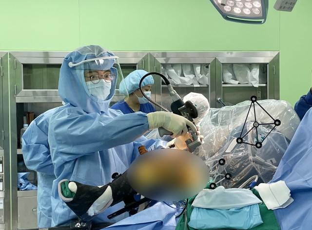부산부민병원 김옥걸 로봇인공관절수술센터장이 마코 로봇을 이용해 고령 환자에게 무릎 인공관절 수술을 하고 있다. 왼쪽 작은 사진은 인공관절 수술로봇 마코. 부산부민병원 제공