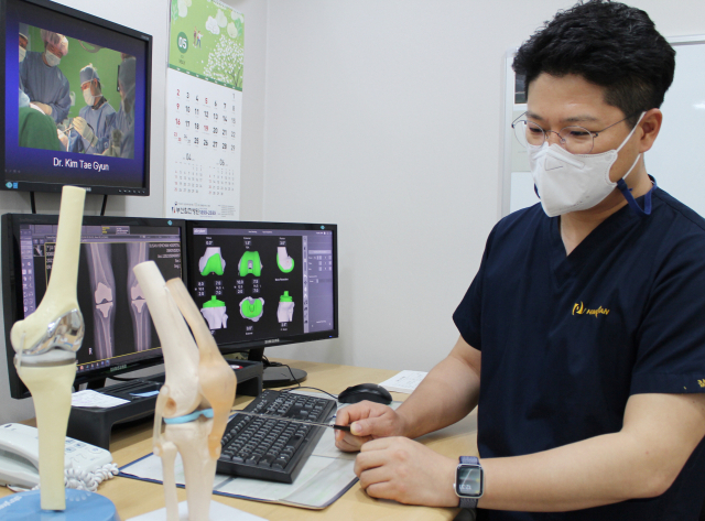 부산힘찬병원 김태균 원장이 다리 변형이 심한 무릎 관절염 환자에게 로봇 인공관절 수술에 대해 설명하고 있다. 부산힘찬병원 제공