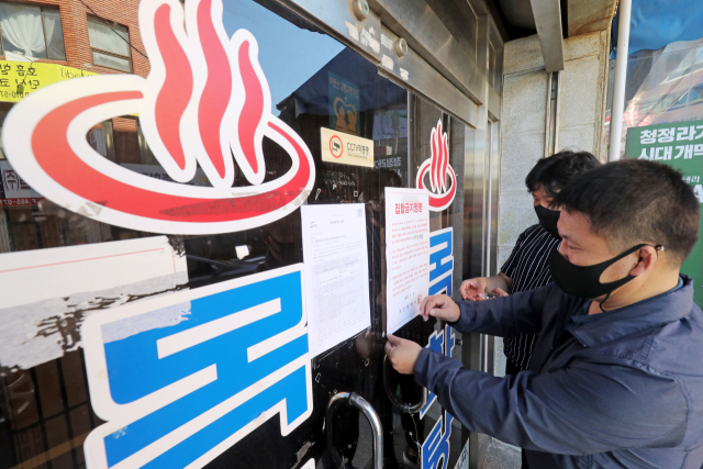 코로나19 발생 이후 1년 동안 부산지역 목욕탕, 노래방, 호프집 등이 크게 감소한 것으로 나타났다. 목욕탕에 집합금지 행정명령 안내문을 부착하고 있는 모습. 부산일보DB