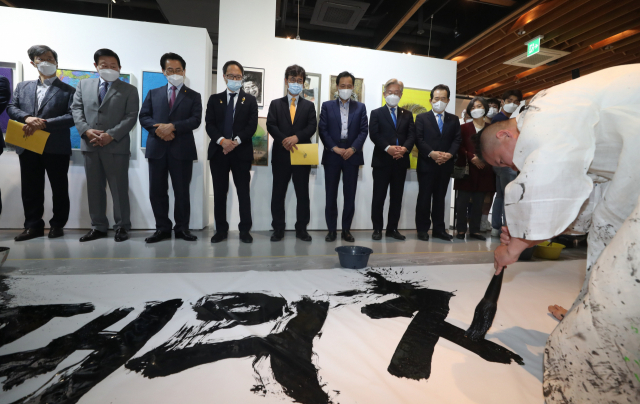 정세균 전 국무총리와 이재명 경기도지사 등 참석자들이 지난 19일 서울 종로구 인사동 마루아트센터에서 열린 노무현 서거 12주기 추모전시에 참석해 권도경 작가의 캘리그라피 퍼포먼스를 보고 있다. 연합뉴스