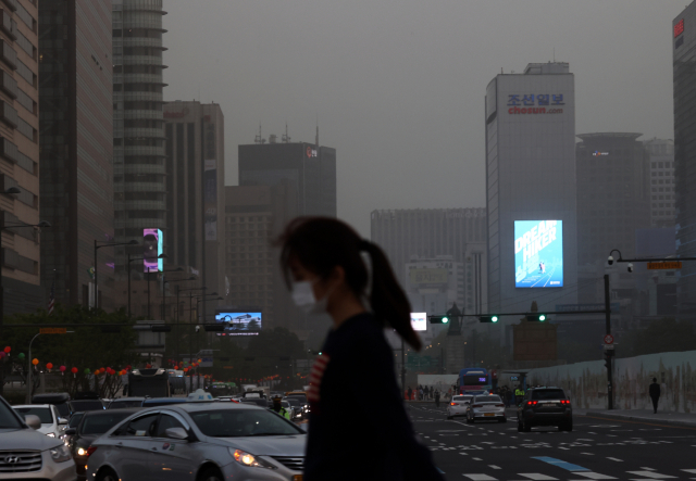 황사로 인해 서울지역에 미세먼지 경보가 발령된 7일 광화문 광장 인근에서 시민이 길을 걷고 있다. 연합뉴스