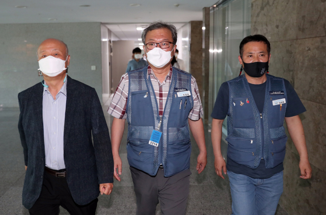 진경호 전국택배노동조합 위원장(가운데), 유성욱 택배노조 CJ대한통운본부장(오른쪽), 박석운 한국진보연대 공동대표 등이 16일 국회 의원회관에서 열린 사회적 합의기구 회의 도중 휴식시간을 이용해 나오고 있다. 연합뉴스