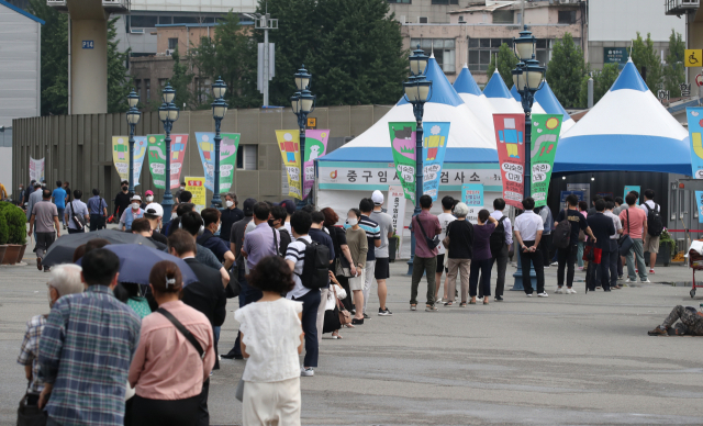 코로나19 신규 확진자 수가 1200명을 넘어선 7일 오전 서울 중구 서울역 임시 선별검사소에서 시민들이 검사를 위해 길게 줄지어 서 있다. 연합뉴스