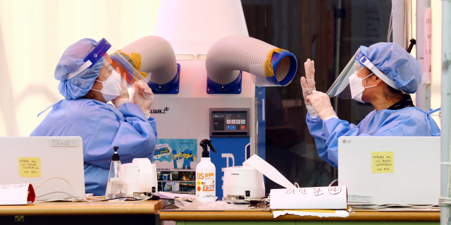 부산에 폭염경보가 내려진 14일 오후 부산 연제구보건소 선별진료소에서 방호복을 입은 의료진들이 냉풍기로 무더위를 달래고 있다. 부산은 사흘째 열대야 현상이 발생하고 폭염특보는 경보로 강화되는 등 연일 무더위가 기승을 부리고 있다. 정종회 기자 jjh@