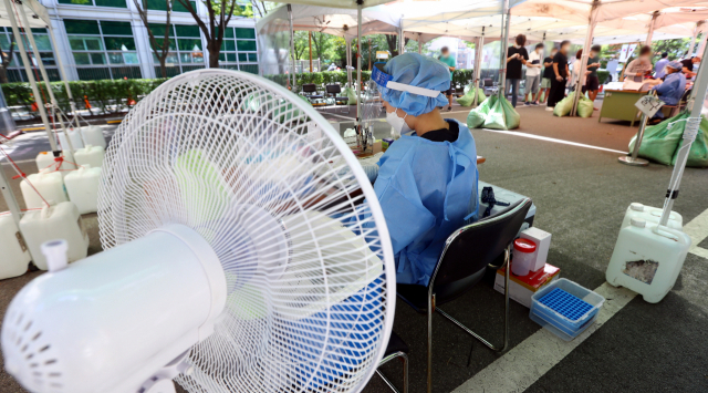 부산에 폭염경보가 내려진 지난 14일 오후 부산 연제구보건소 선별진료소에서 방호복을 입은 의료진들이 선풍기로 무더위를 달래고 있다. 정종회 기자 jjh@