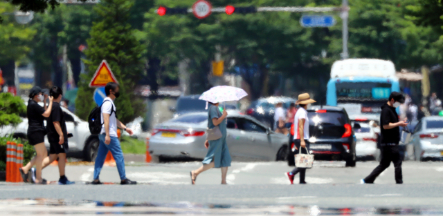 부산 지역에 일주일째 폭염 특보가 내려진 지난 15일 부산 해운대구 벡스코 인근에서 시민들이 지열로 아지랑이가 피어오르는 건널목을 지나가고 있다. 정종회 기자 jjh@