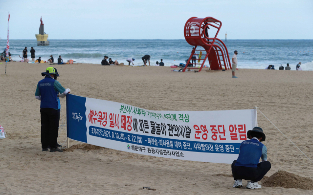 사회적 거리 두기를 4단계로 격상함에 따라 폐장을 하루 앞둔 9일 오후 해운대해수욕장 시설관리사업소 직원들이 백사장에 폐장 안내 현수막을 설치하고 있다. 김경현 기자 view@