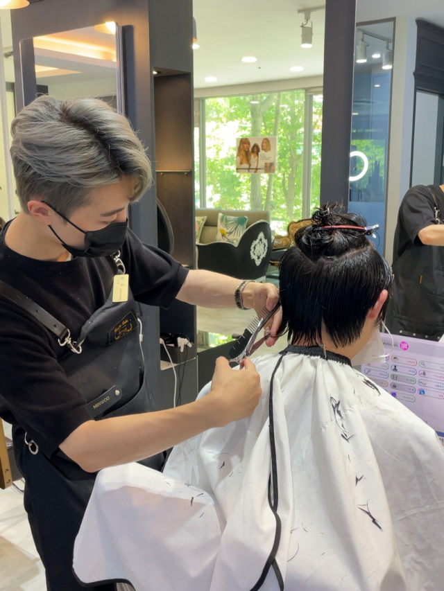 김법현(왼쪽) 민우헤어 원장이 고객의 헤어스타일을 다듬고 있다. 동의과학대 제공