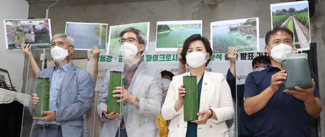 24일 오전 서울 종로구 환경운동연합에서 열린 ‘낙동강·금강 독성 마이크로시스틴 현황 분석 결과 발표 기자회견’에서 참석자들이 낙동강에서 뜬 물과 그 당시 사진 등을 들어 보이고 있다. 연합뉴스