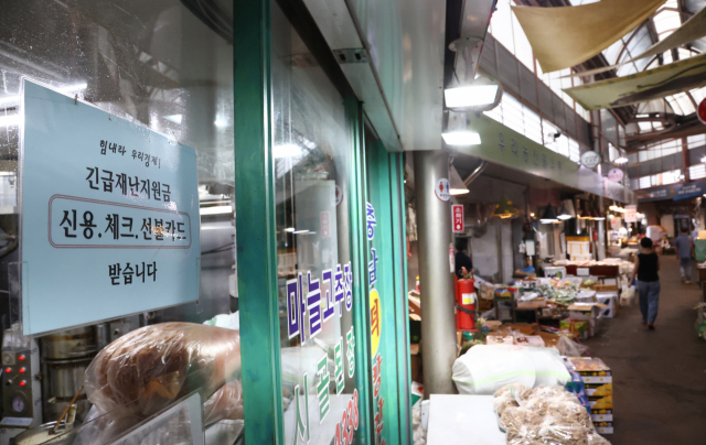 정부가 추석 전 코로나 상생국민지원금 지급을 결정한 26일 오전 서울 종로구 통인시장 점포에 긴급재난지원금 관련 안내문이 붙어 있다. 상생국민지원금은 기본적으로 가구소득 하위 80% 이하인 가구의 구성원이 대상이다. 추가로 1인 가구와 맞벌이 가구에 특례기준이 적용돼 전 국민의 약 88%가 받는다. 가구 구성원 1인당 25만원씩, 4인 가구라면 100만원, 5인 가구라면 125만원이 지급된다. 연합뉴스