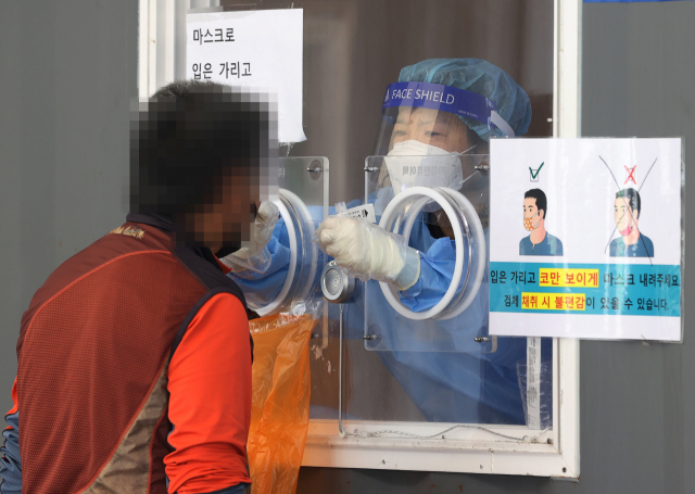 추석 연휴가 끝나고 코로나19 신규 확진자가 연일 폭증하면서 3천명을 넘어선 가운데 25일 오전 서울역 광장에 마련된 중구임시선별검사소에서 의료진이 검체를 채취하고 있다. 연합뉴스