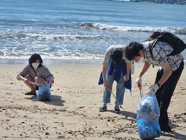 부산 지역 시민들의 쓰레기 줍기 모임 “금뿌리” 멤버들이 광안리 해수욕장에서 쓰레기를 줍는 모습.