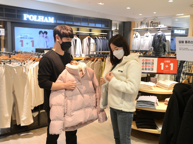 위드 코로나와 갑작스럽게 추워진 날씨 영향으로 코트, 패딩, 퍼(fur) 등 겨울철 외출용 의류를 찾는 고객이 늘고 있다. 롯데백화점 부산본점 7층 폴햄 매장에서 한 고객이 겨울용 인기 의류를 입어보고 있다. 롯데쇼핑 제공