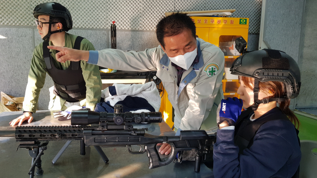 SNT 모티브의 송병조 책임이 총을 처음 잡아본 부산일보 영상팀원에게 K14 저격 소총 사격 요령을 설명하고 있다. 10분 후 사격 초보자인 부산일보 영상팀원은 백발백중의 저격 실력을 선보여 주위를 놀라게 했다.