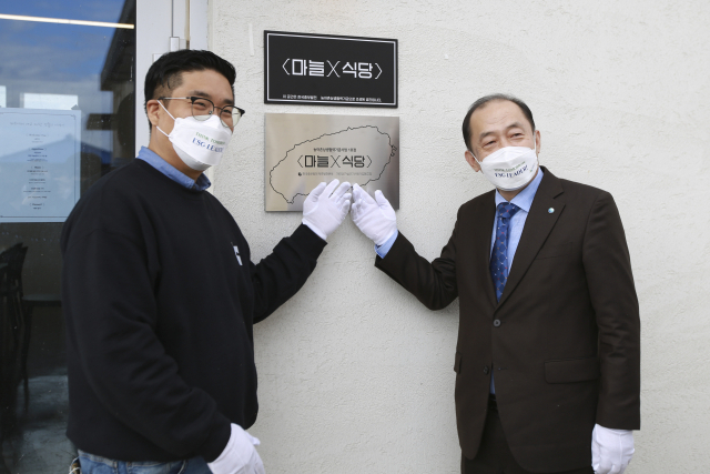2일 제주 대정읍에서 ‘마늘X식당’ 오픈기념 현판 제막식 후 김호빈 한국중부발전 사장(오른쪽), 김영민 제주폐가살리기협동조합 이사장이 기념촬영을 하고 있다. 중부발전 제공