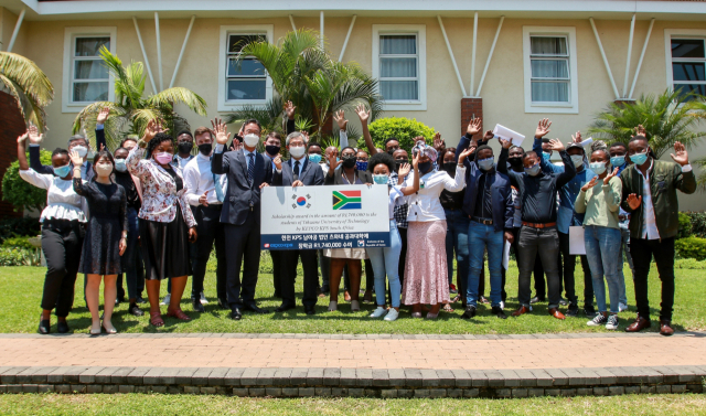 신용래 한전KPS 지사장(피켓 맨 왼쪽)과 박철주 주남아공 대한민국 특명 전권 대사(지사장 오른쪽 첫 번째), Dr.Grace Kanakana 츠와네 공과대학 학장(지사장 오른쪽 두 번째) 및 장학생들이 장학증서 전달식 기념촬영을 하고 있다. 한전KPS 제공