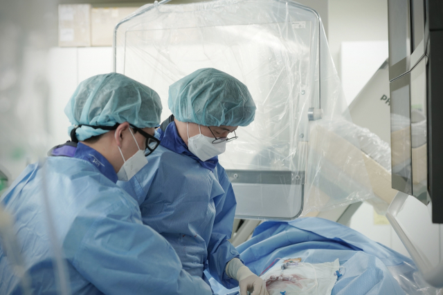 동남권원자력의학원 뇌종양·뇌혈관센터 이현곤(오른쪽)과장이 대뇌 동맥류 환자의 부푼 동맥류 안을 코일로 막아주는 코일 색전술을 시행하고 있다. 동남권원자력의학원 제공