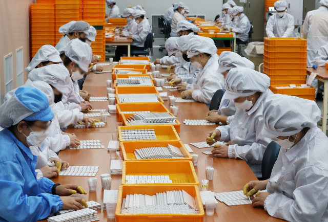 오미크론에 의한 확진자 폭증으로 자가검사 키트의 품귀 현상이 지속되자 정부는 다음 달 5일까지 일인당 구매 수량을 5개로 제한했다. 경기도 수원시 권선구의 자가검사 키트 공장에서 직원들이 키트를 생산하고 있다. 연합뉴스