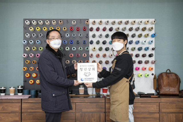 한국중부발전 서한석 ESG경영처장(왼쪽)과 3기 창업팀 ‘업투유’ 대표가 청년상회 현판을 들고 기념촬영을 하고 있다. 중부발전 제공