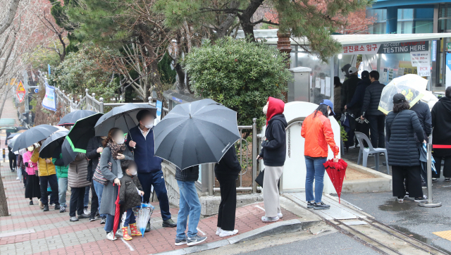 봄비가 내린 13일 부산 해운대구보건소 선별검사소에서 시민들이 코로나19 검사를 위해 길게 줄을 서 있다. 정대현 기자 jhyun@