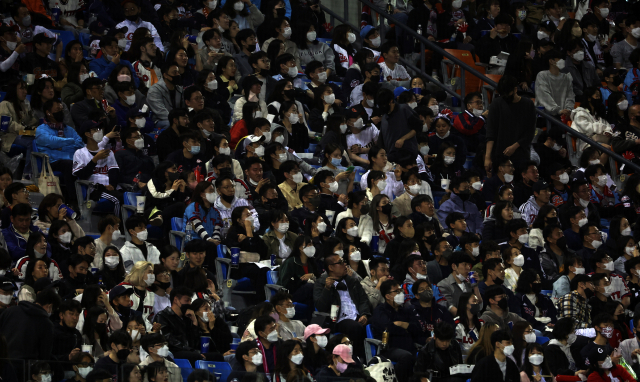 지난달 29일 잠실야구장에서 관중들이 마스크를 쓰고 프로야구 경기를 관람하고 있다. 정부는 2일부터 실외 마스크 착용 의무를 해제했지만 집회 참가인원이나 공연, 스포츠경기 관람객이 50명이 넘을 경우에는 실외라도 마스크를 써야 한다. 연합뉴스