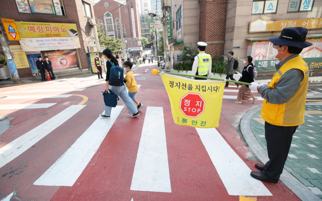 서울 성북구의 한초등학교 앞 어린이보호구역에서 경찰과 교통안전 자원봉사자들이 학생들의 등교를 돕고 있다. 연합뉴스