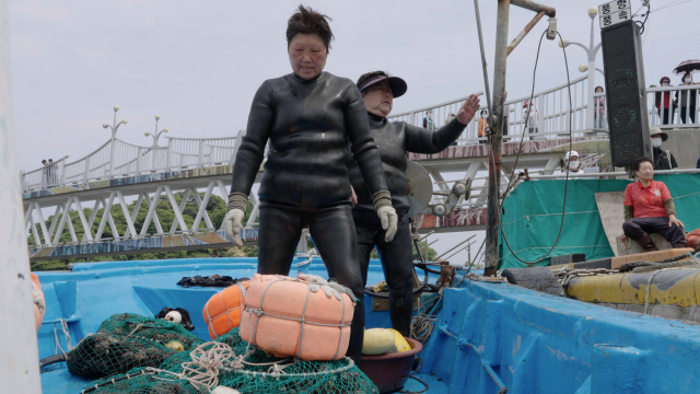 정정순 해녀(왼쪽)가 선박 위에서 잡아온 해산물을 뭍으로 옮기고 있다. 정수원 PD blueskyda2@busan.com