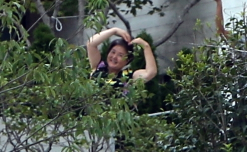 전국에서 온 문재인 전 대통령 지지자들이 17일 낮 문재인 전 대통령 사저가 있는 경남 양산시 하북면 지산리 평산마을에 모여 평산마을 평온 회복과 문 전 대통령 부부 안녕을 기원하는 집회를 했다. 문 전 대통령 부인 김정숙 여사가 사저 바깥으로 잠깐 나와 조경수 사이로 지지자들을 향해 손으로 하트를 만들고 있다. 연합뉴스