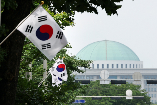 제74주년 제헌절인 17일 서울 영등포구 여의도동 거리에 게양된 태극기 뒤로 국회의사당이 보인다. 여야는 이날까지도 21대 후반기 국회 원 구성 협상을 마무리 짓지 못하고 사실상 입법부의 공백 상태로 제헌절을 맞이했다. 연합뉴스