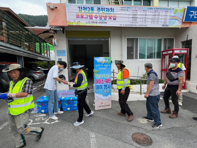 부산 사하구청 소속 살수차가 8일 당리동 한 도로에서 물을 뿌리며 무더위로 달궈진 도로 열기를 식히고 있다(위). 사하구청이 지난달 28일 감천2동 행정복지센터에서 자활근로자들에게 얼린 생수를 나눠주고 있다. 부산 사하구청 제공