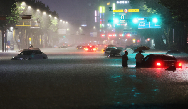 8일 밤 서울 강남구 대치역 인근 도로가 물에 잠기면서 차량과 보행자가 통행하는 데 불편을 겪고 있다. 연합뉴스
