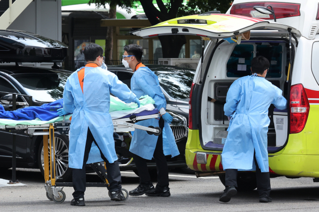 21일 수도권 주말 당번병원으로 지정된 서울 국립중앙의료원에서 119 구급대원들이 코로나19 중증환자를 음압병동으로 이송하고 있다. 연합뉴스