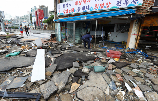 6일 오전 부산 서구 송도해수욕장 일대 상가와 도로가 강한 파도에 파손돼 있다. 아스팔트 더미가 파도와 함께 휩쓸려 들어가면서 상가들의 피해가 더 커졌다. 정종회 기자 jjh@