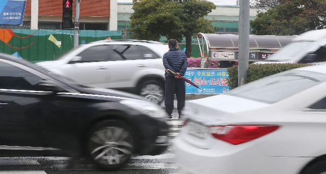 부산 동구 부산진역 앞 한 건널목에서 신호등이 바뀌는 바람에 미처 길을 다 건너지 못한 한 노인이 양옆으로 차가 지나가는 도로 중간에 서서 다음 신호를 기다리고 있다.부산일보DB