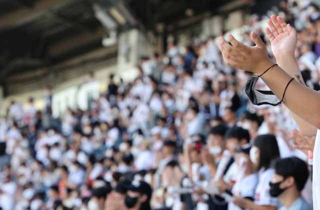 25일 오후 서울 잠실야구장에서 마스크를 손목에 건 한 관중이 프로야구 경기를 관람하고 있다. 26일부터 실외 마스크 착용 의무가 완전히 해제됐다. 당장 이번 가을 포스트시즌을 비롯해 야외 공연, 대규모 집회 등에서 마스크를 쓰지 않아도 된다. 연합뉴스