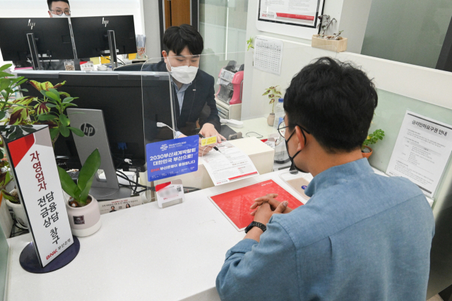 자영업자를 대상으로 고금리의 사업자 대출을 저금리로 전환해주는 프로그램이 시행된다. 한 자영업자가 부산은행 창구에서 대출을 상담하고 있다. 부산은행 제공