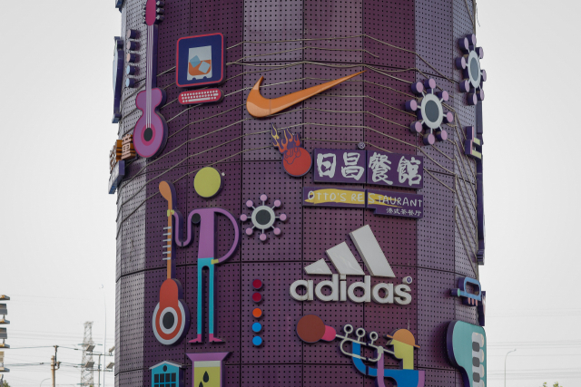 26일 영국 런던의 한 환전소 앞으로 시민이 지나가고 있다. 아래쪽은 유명 외국 브랜드 로고들이 붙어 있는 중국 베이징 한 쇼핑몰. 최근 달러 강세로 인해 파운드화, 위안화 등의 가치가 연일 폭락하고 있다. AP연합뉴스·EPA연합뉴스