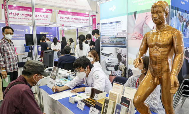 코로나19 팬데믹 이후 3년 만에 전면 오프라인 행사로 치러진 ‘2022 부산국제의료관광컨벤션’이 성황리에 끝마쳤다. 참석 내빈들이 행사의 시작을 알리는 개막 축포 스위치를 누르는 모습(위)과 부스에서 건강 상담을 받는 참관객들. 김종진 기자 kjj1761@