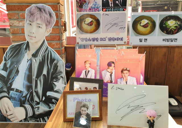 BTS RM이 방문한 후 팬들이 ‘동래밀면’ 탁자의 한 구석을 BTS 사진들로 꾸몄다.