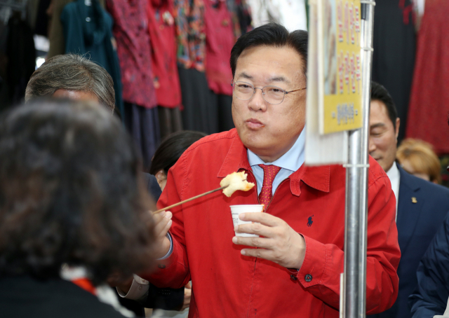 국민의힘 정진석 비상대책위원장이 13일 대구 중구 서문시장을 찾아 상인들과 인사하며 어묵을 먹고 있다. 연합뉴스