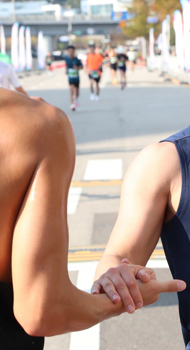 10km 코스에 참가한 한 주자가 결승선을 통과하며 먼저 들어온 동료와 손을 마주치고 있다. 정대현 기자