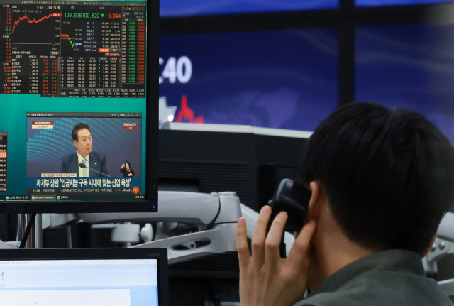 27일 오후 서울 중구 을지로 하나은행 본점 딜링룸에서 한 외환딜러가 컴퓨터 화면에 이날 윤석열 대통령 주재로 열린 비상경제민생회의 생중계 화면을 시청하며 업무를 보고 있다. 연합뉴스